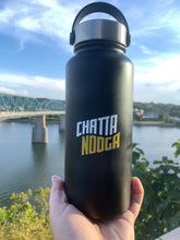 Cargar imagen en el visor de la galería, 32 ounce wide mouth, black powdered finish insulated water bottle with loop handle. Logo is Chatta on top in white and Nooga on bottom in gold.
